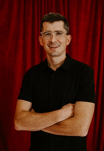 Trevor Tennant smiling in front of a red wall